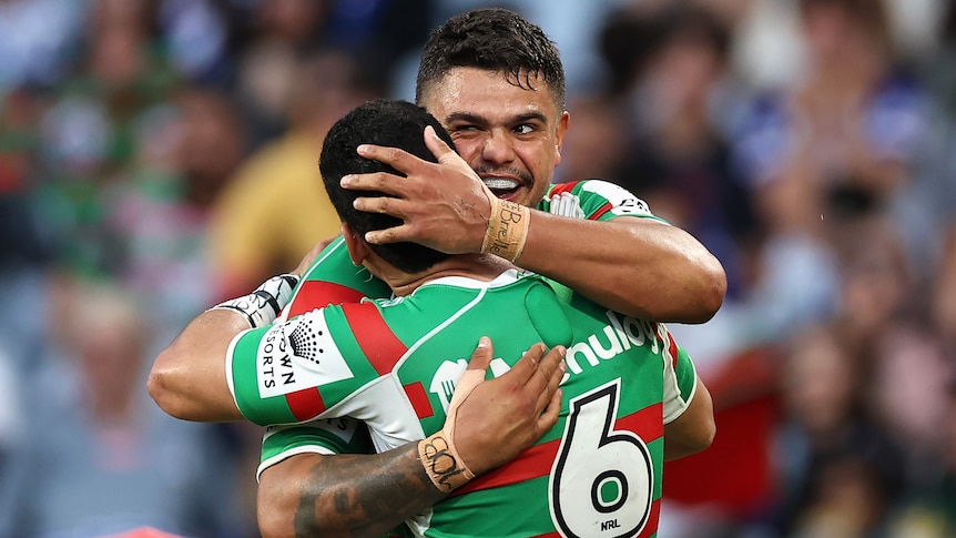 Two South Sydney Rabbitohs NRL players embrace as they celebrate a try.