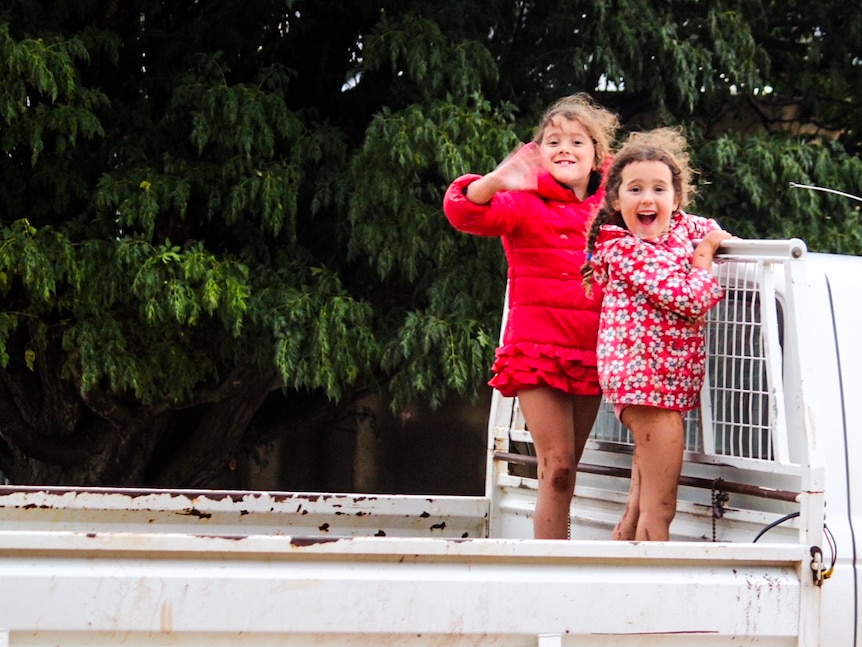 Elsie and her sister Maeve on the back of a ute.