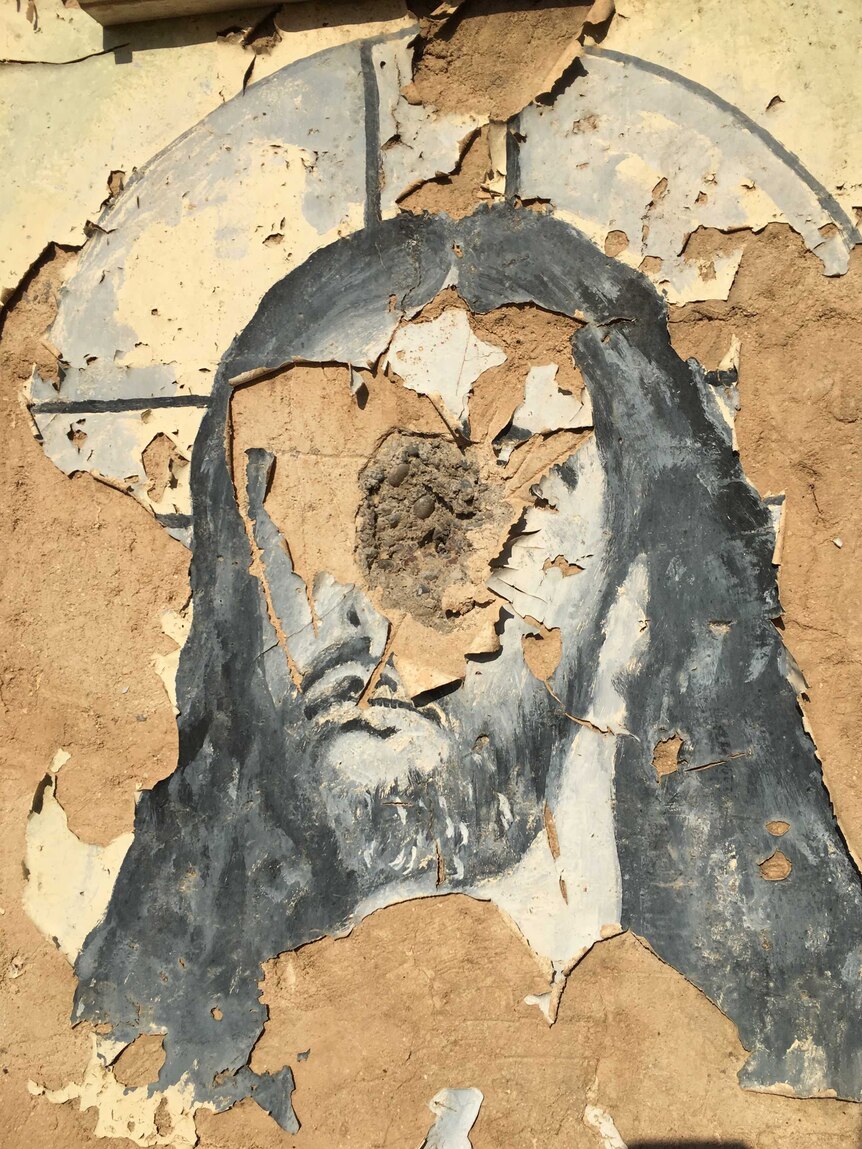 A mural of Jesus Christ, scattered with bullet holes
