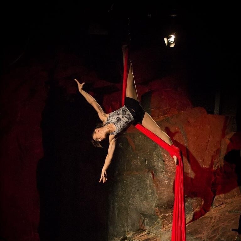 Gymnast coach and circus performer Anna McGoldrick upside down in circus silks in front of a rock wall