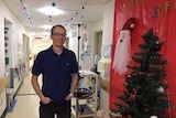 Patient Joshua Leveridge stands in a hospital ward hallway decorated for Christmas.