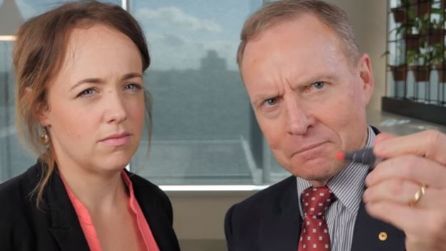 Woman glaring with David Morrison next to her looking serious, holding pen