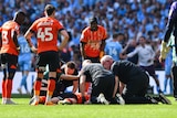 Doctors surround a player collapsed on the ground.