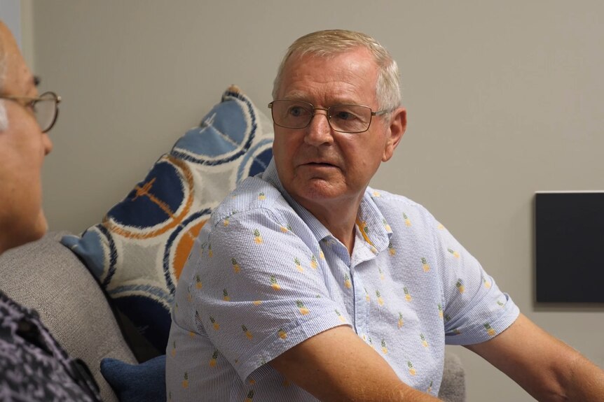 An elderly man sitting down looks across to his doctor. 