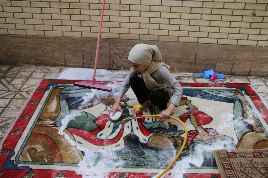 A girl washing a rug during Nowrooz in 2018.