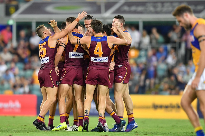 Brisbane Lions players celebrate in a huddle after scoring a goal against West Coast Eagles