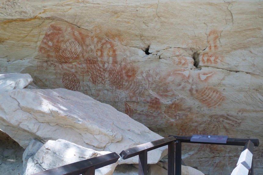 Sandstone with Aboriginal rock art painted on in a red-orange colour.