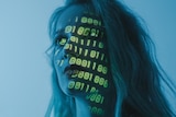 Code over a womans face in a dark room. 