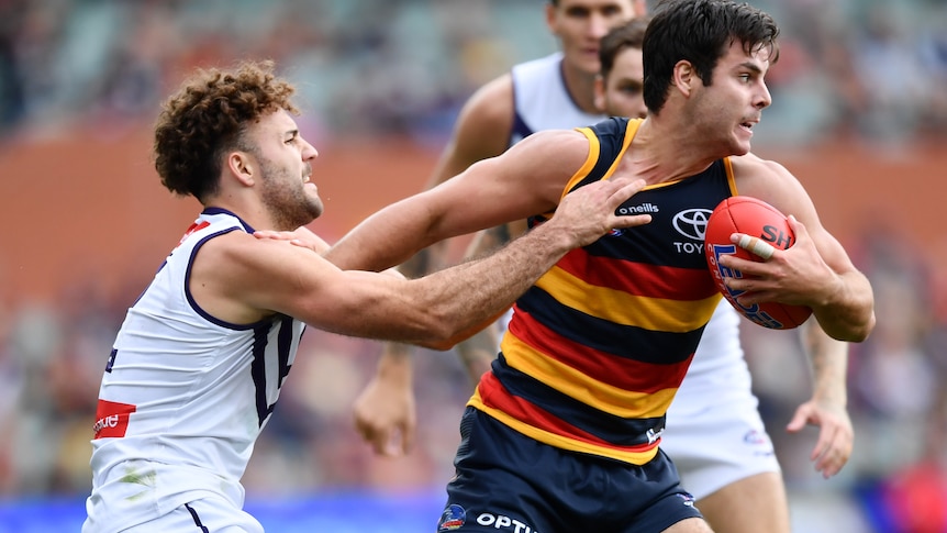 Darcy Fogarty holds the football and tries to fend off Griffin Logue, who has hold of his jersey