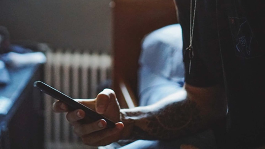 Man scrolling through his phone on bed while experiencing insomnia during coronavirus