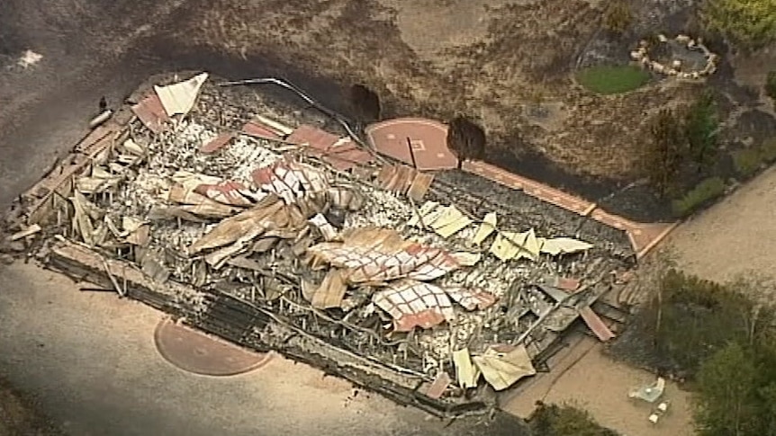 A large property destroyed by fire with the block covered in damaged building materials.