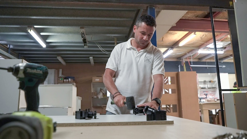 Chris Nowaczyk working with a hammer and board. 