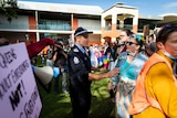 Police speak to a woman at a Maylands protest for and against drag queen story time.