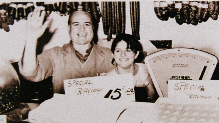 An early photo of Giuseppe 'Joe' Piedimonte and his granddaughter in the deli, waving to the camera