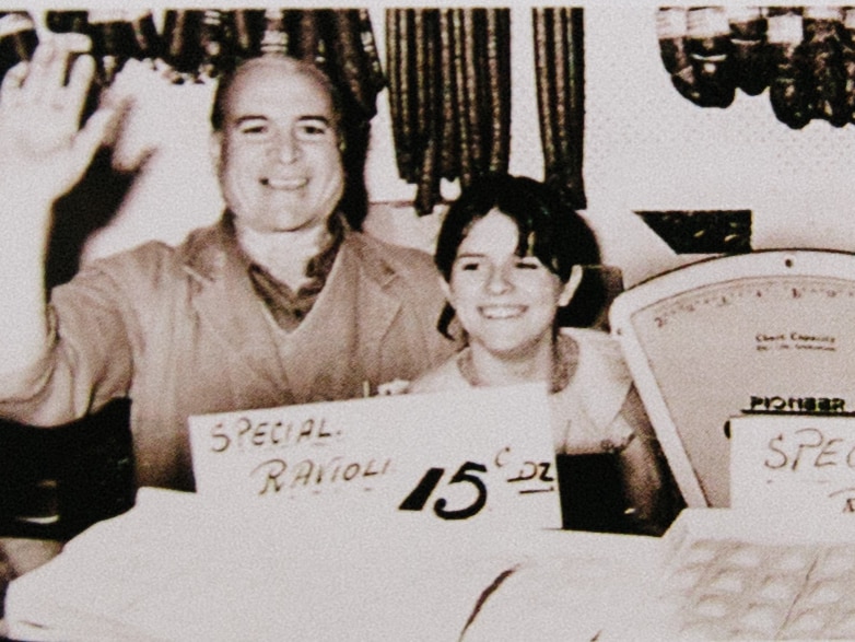 An early photo of Giuseppe 'Joe' Piedimonte and his granddaughter in the deli, waving to the camera