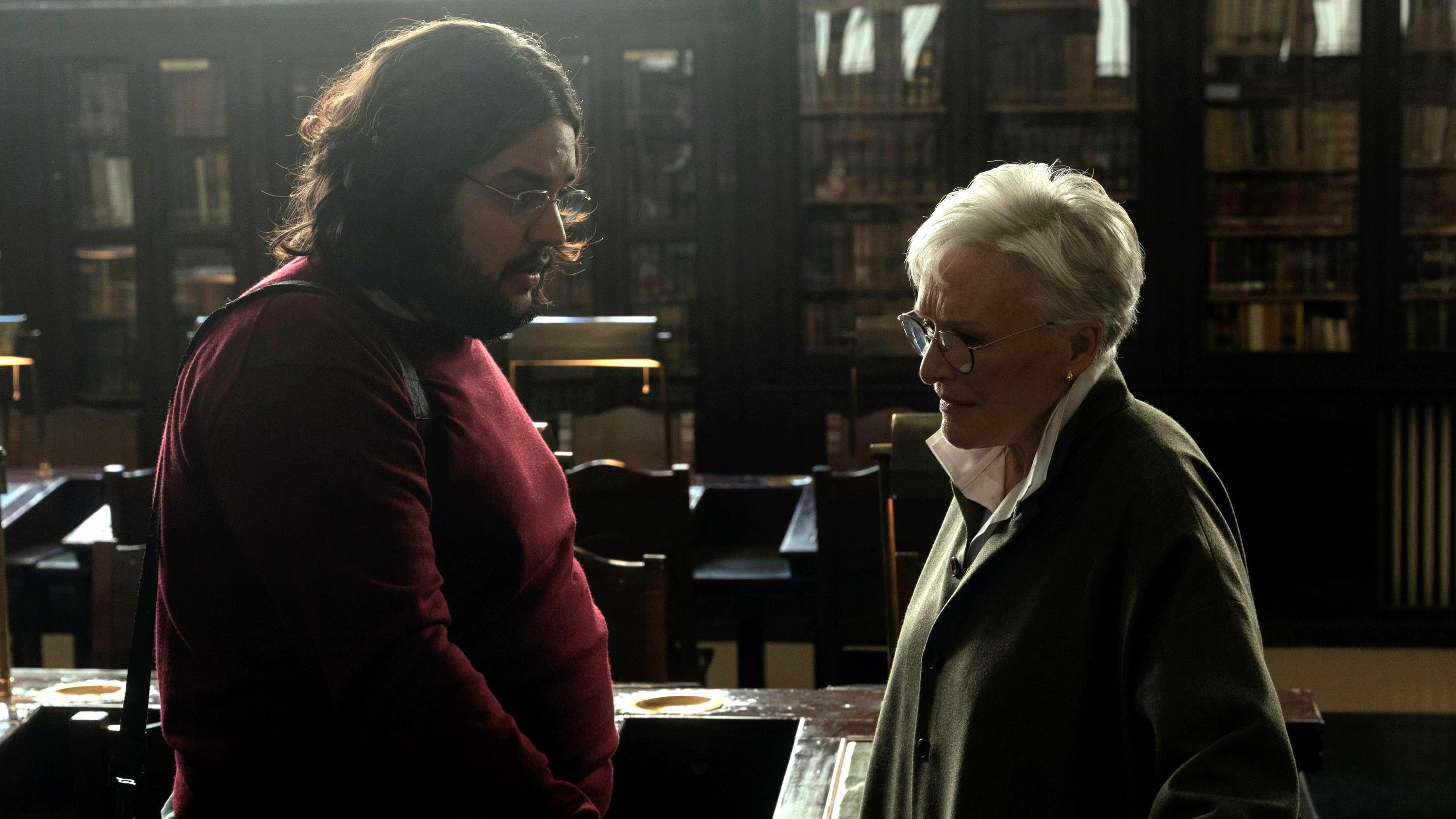 A man and a woman stand opposite each other in a library.