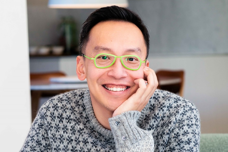 Headshot of smiling Alvin Quah, smiling widely, wearing bright green-framed glasses