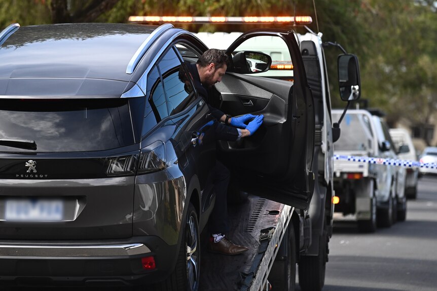 a police officer investigates the inside of a car