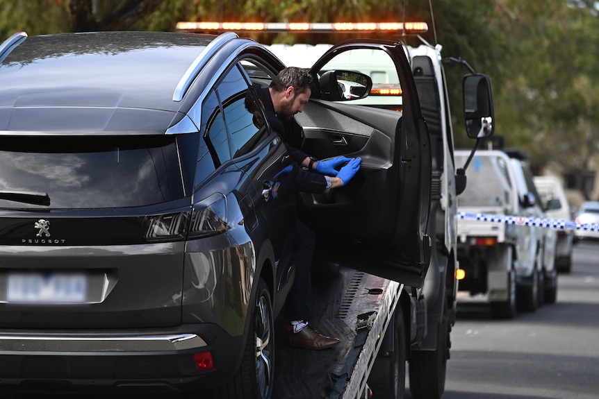 a police officer investigates the inside of a car