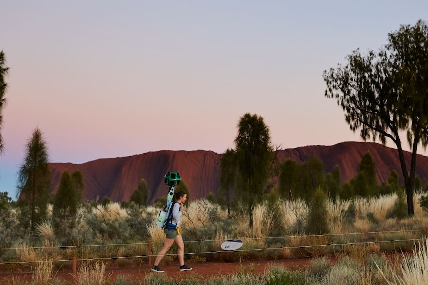 A girl treks with Google street-view camera.