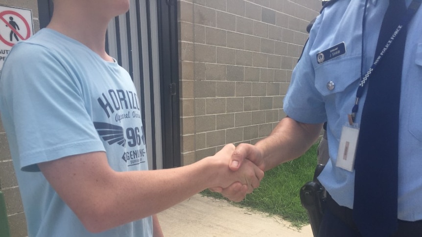 A young boy shaking hands with a man in a police uniform.