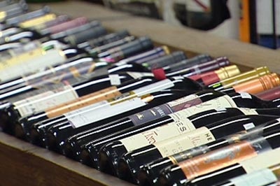 Various differently labelled Wine bottles lie on a shelf in a bottle shop
