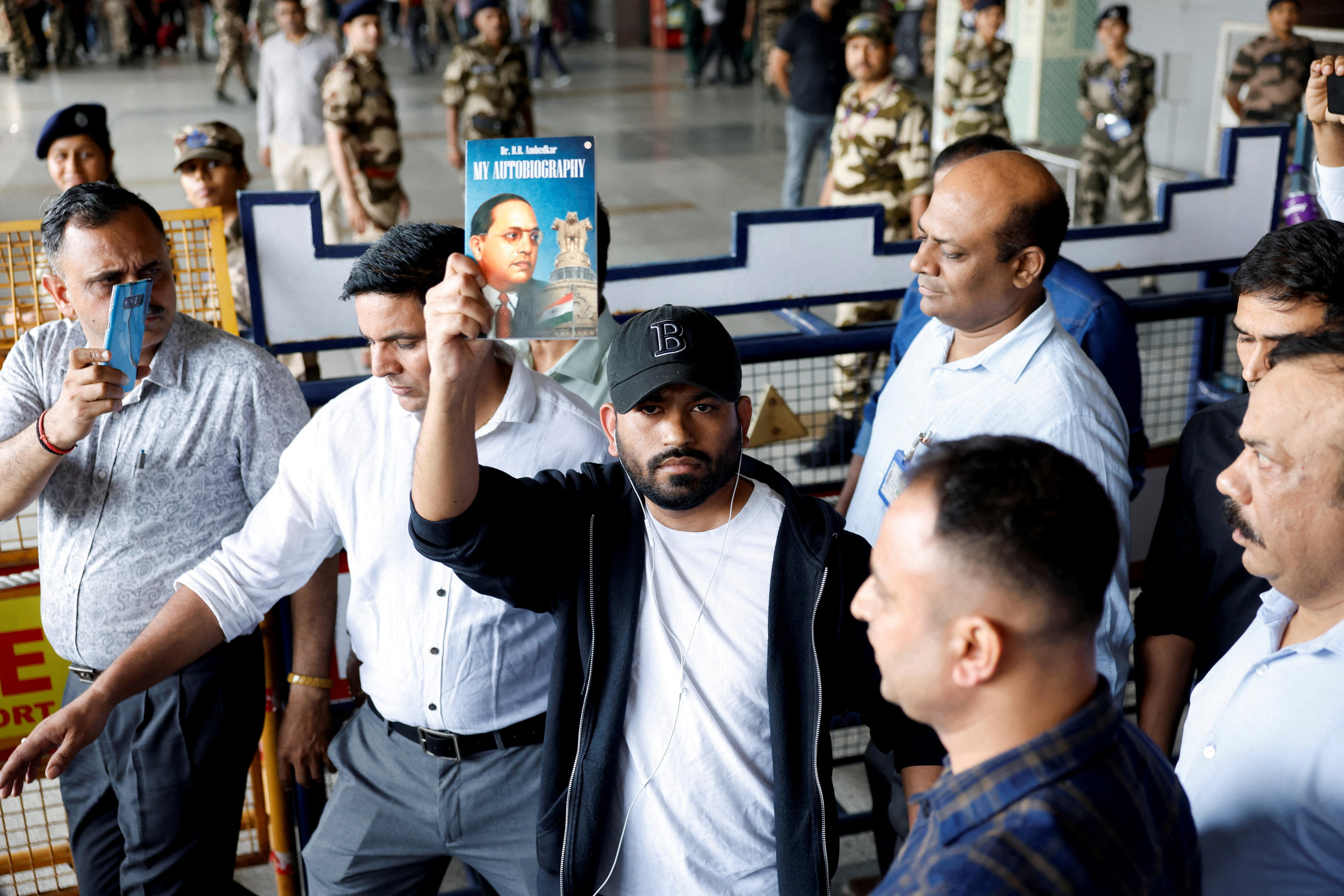 Abhijeet Dipke, head of the Cockroach Janta Party (CJP), holds a book as he leaves Delhi airport.
