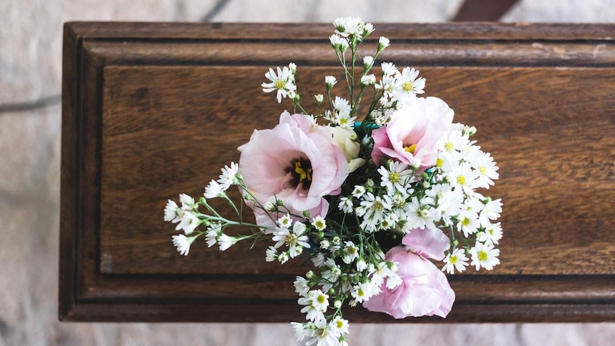 Pink flowers on a wooden coffin.