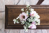 Pink flowers on a wooden coffin.