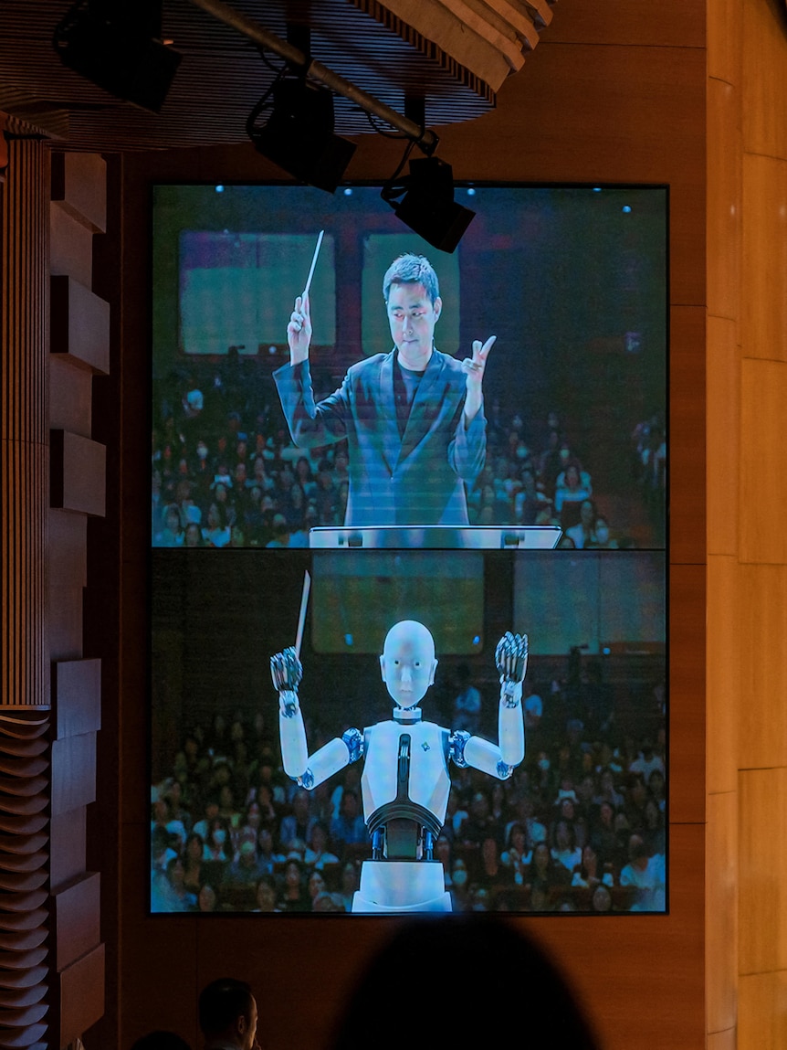 Conductor Choir Soo-yeoul and humanoid robot EveR 6 projected on-screen during performance.