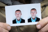 A woman's fingers hold a passport photo of a young Ukrainian man.