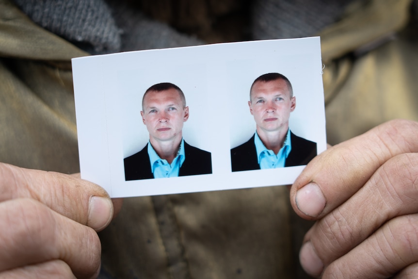 A woman's fingers hold a passport photo of a young Ukrainian man.