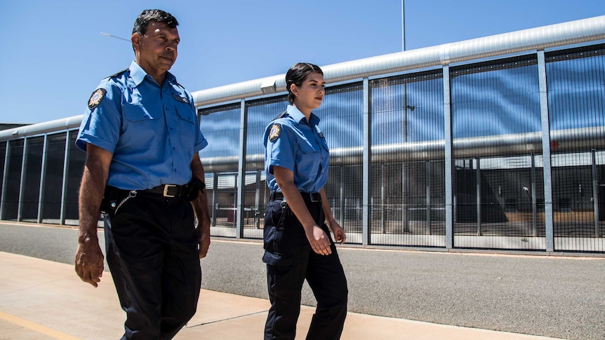 Prison officers walking along fence line