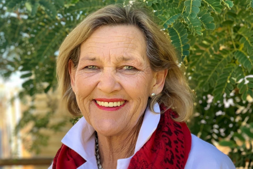 Carmel Meurant smiles at the camera while standing in front of a tree.