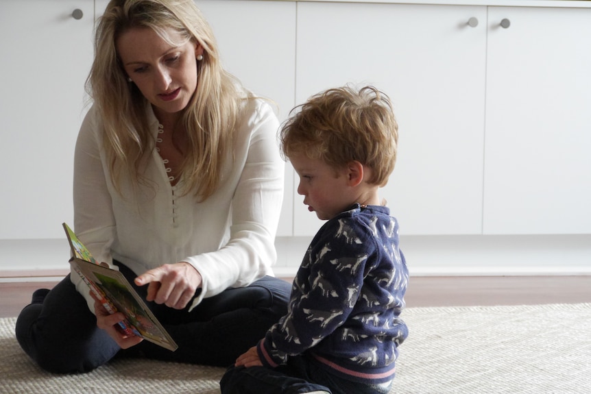 Woman reads a picture book to her young son.