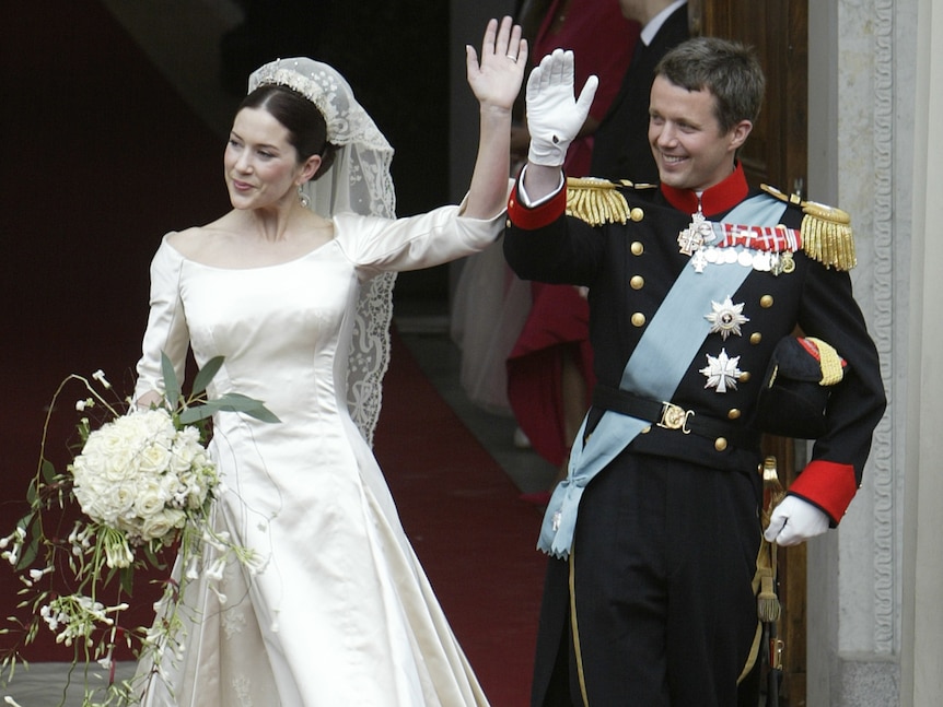 Mary and Frederik outside the church wave to onlookers in wedding garb