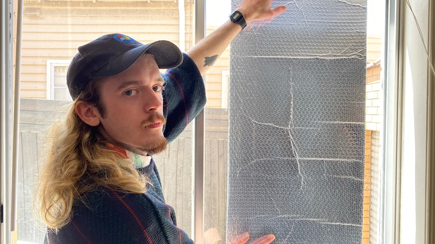 A man puts up a foil against a window.