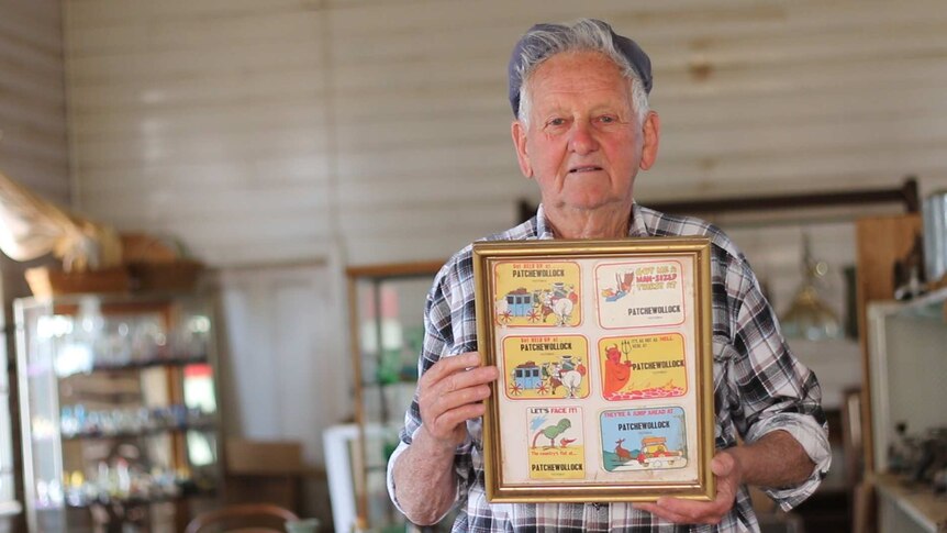 A local Patchewollock man holds up a series of coasters from his collection.