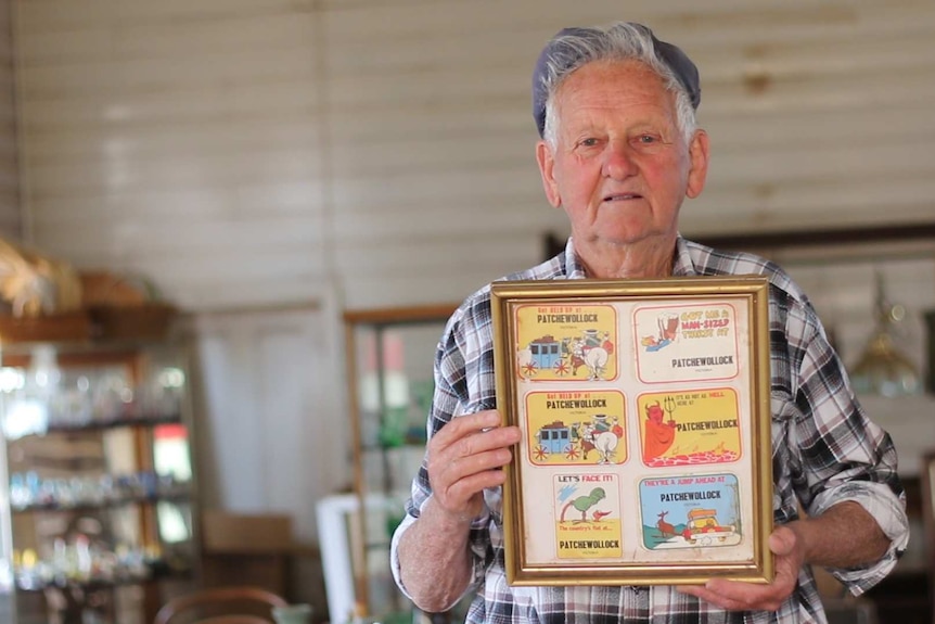 A local Patchewollock man holds up a series of coasters from his collection.