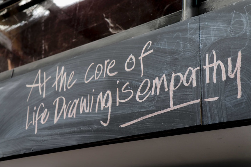 A blackboard sign at an art studio that reads "At the core of Life Drawing is empathy"