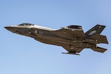 A jet fighter flies over a clear sky.