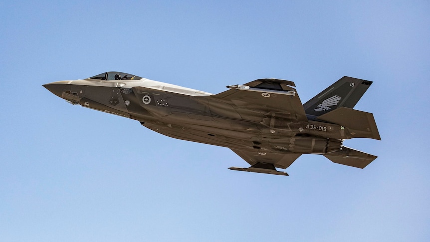 A jet fighter flies over a clear sky.