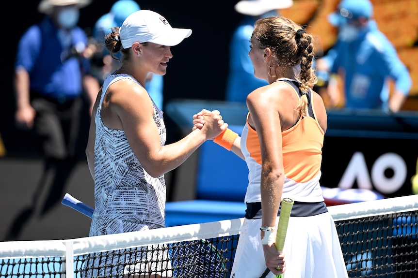 Two female tennis players shake hands at the net.