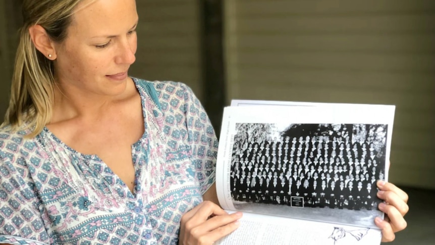 A woman looks at an old photo.