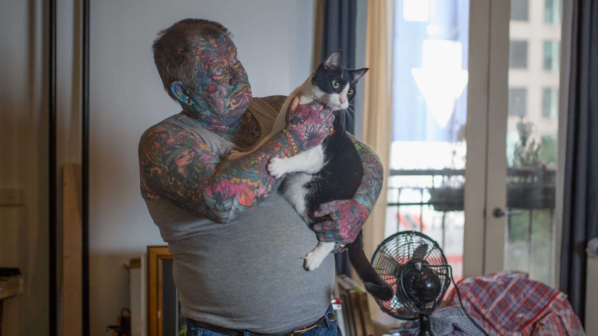 John holds his cat, Lucky Devil.