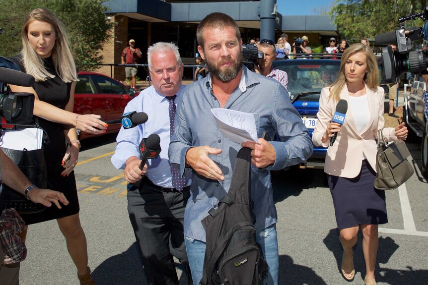 Ben Cousins walks away from Armadale Magistrates Court holding a backpack and piece of paper with journalists trailing behind.