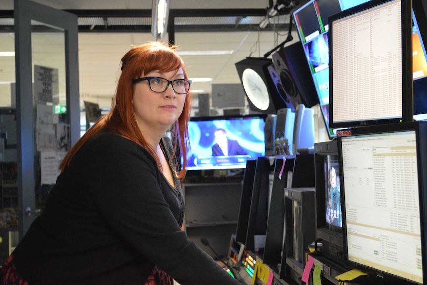 Emma Williams looks at two computer screens in the news room.