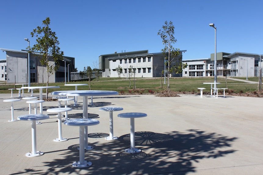 Outdoors with grey and white buildings in the background and seating in the foreground