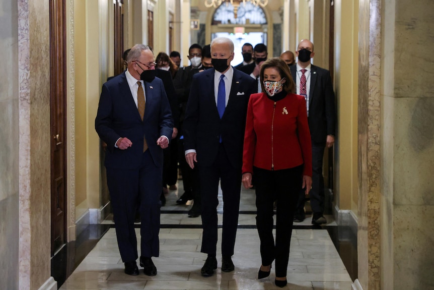 US President Joe Biden is flanked by Senate Majority Leader Chuck Schumer and House Speaker Nancy Pelosi.