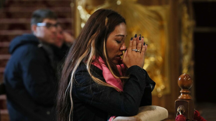 Woman praying in nave of Saint Peter's Basilica, Vatican City.
